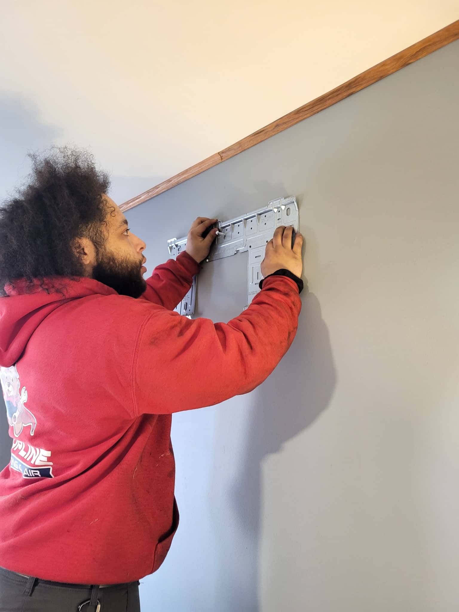 Air Benders technician mounting a mini-split bracket plate on a customer's wall