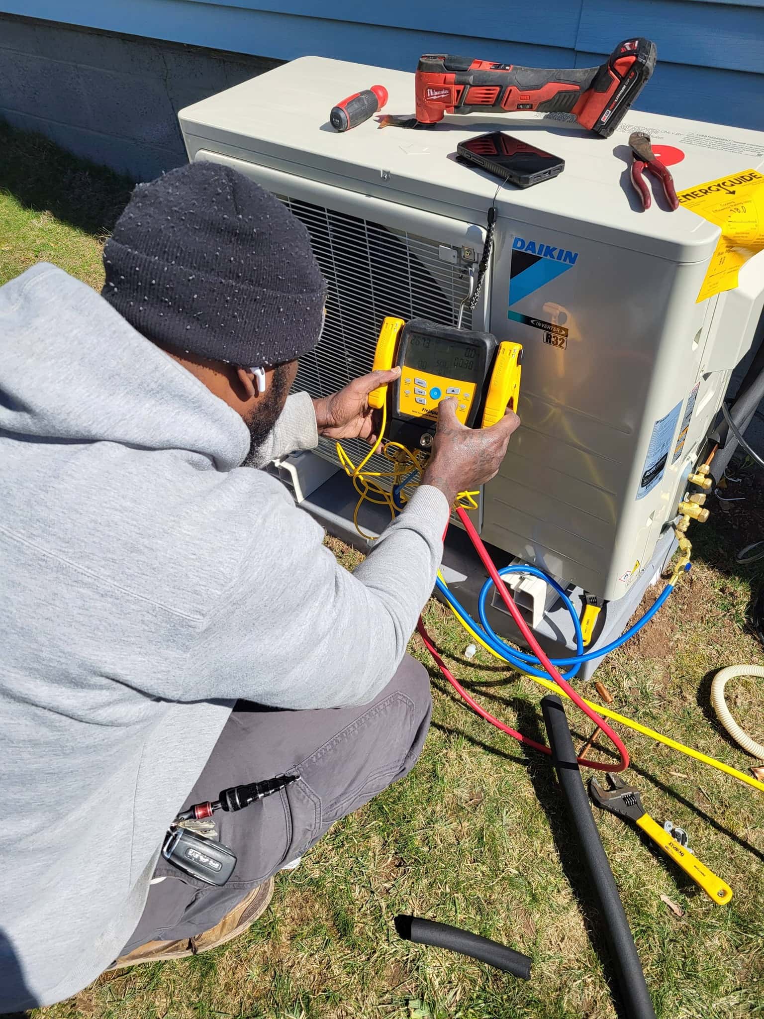 Air Benders technician using diagnostic gauges on a Daikin outdoor condenser at a customer's home