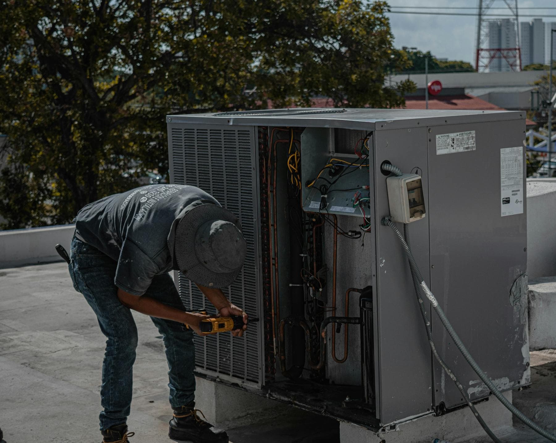 Technician repairing rooftop air conditioning equipment