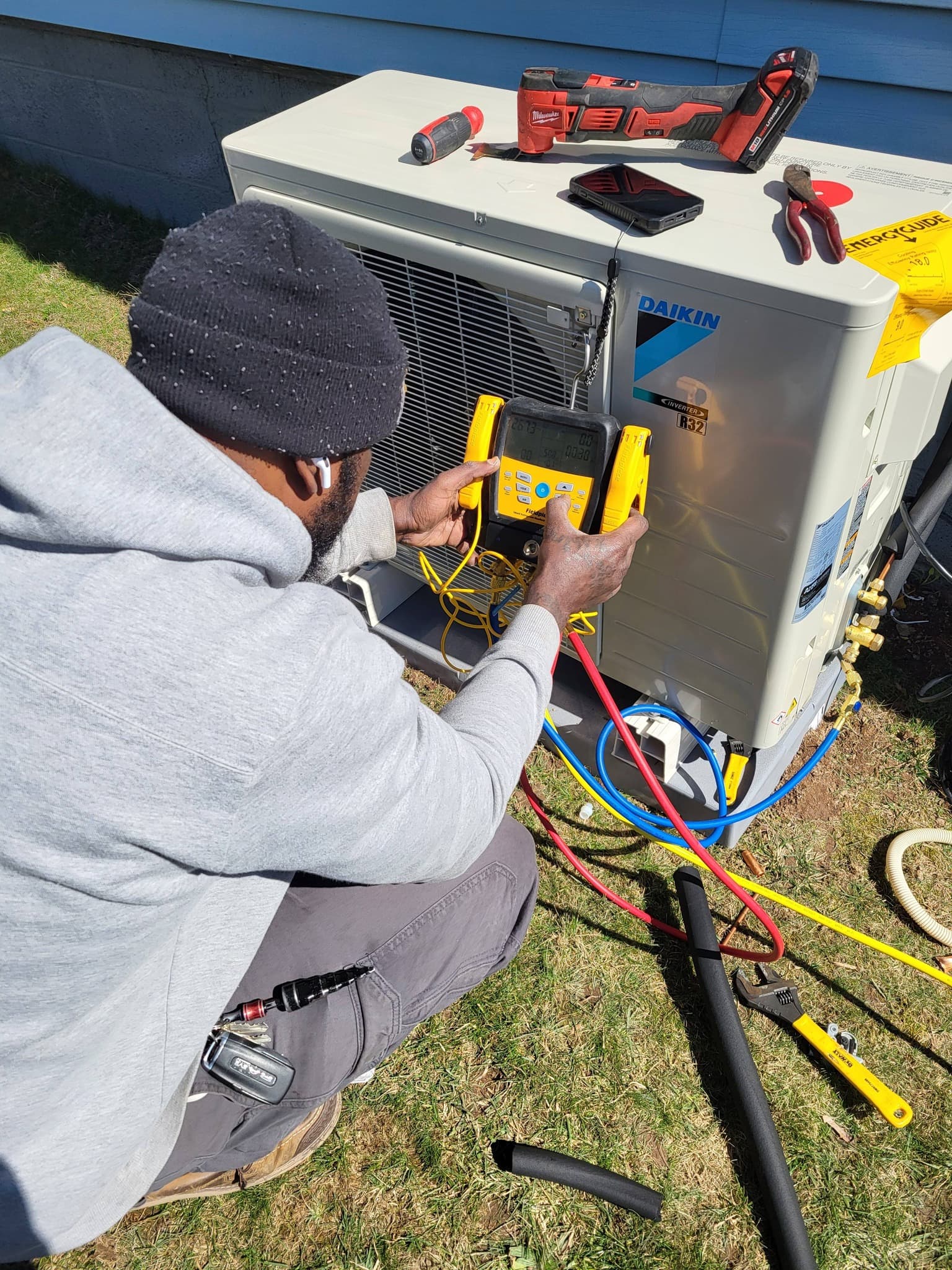 Air Benders technician using diagnostic gauges on a Daikin outdoor condenser at a customer's home